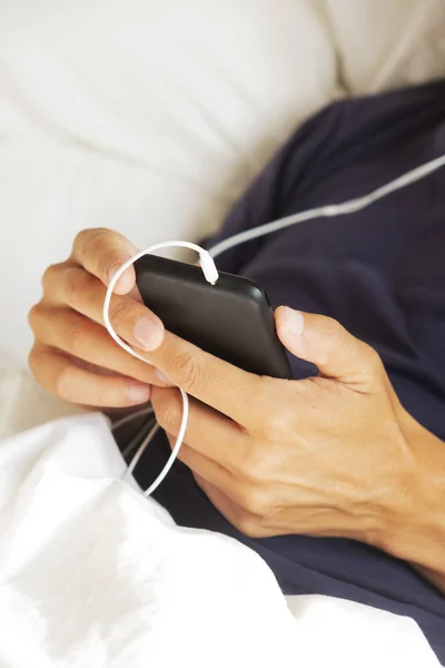 Νέος άνθρωπος χρησιμοποιώντας το smartphone του στο κρεβάτι — Φωτογραφία Αρχείου