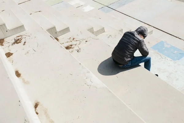 Homem enrolado sentado em uma escada ao ar livre — Fotografia de Stock