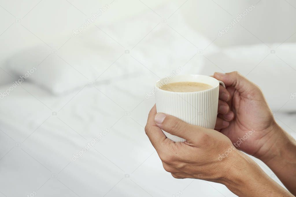 man having a coffee in a bedroom