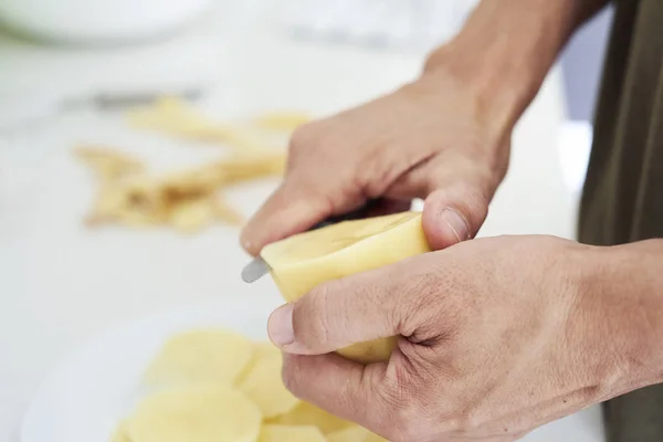 Man skär tunna skivor av potatis — Stockfoto