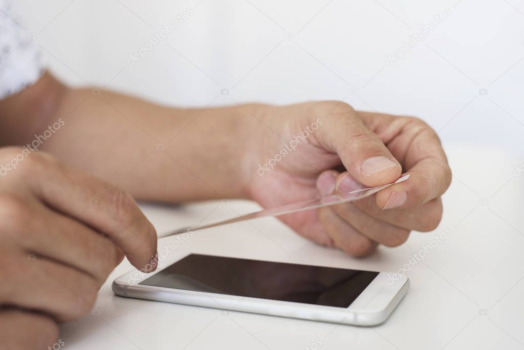 man installing a screen protector in a smartphone
