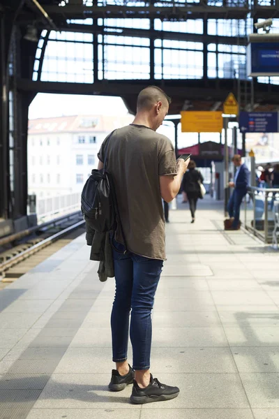 Hombre usando smartphone en una estación de tren en Berli — Foto de Stock