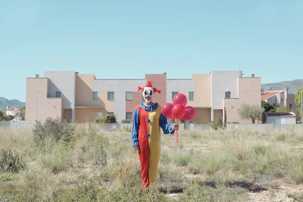 Clown spaventoso con un mucchio di palloncini all'aperto — Foto Stock