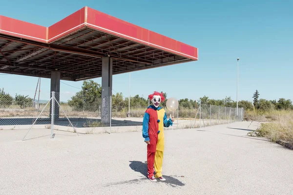 Straszny clown z złotym balonem na zewnątrz — Zdjęcie stockowe