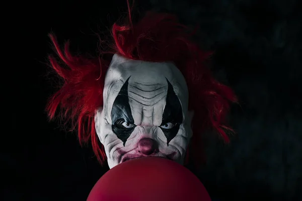 Palhaço do mal assustador com um balão vermelho — Fotografia de Stock