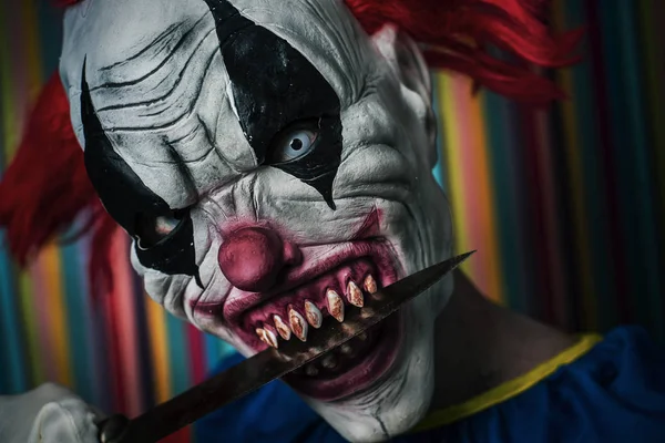 Gruseliger böser Clown mit Messer im Mund — Stockfoto