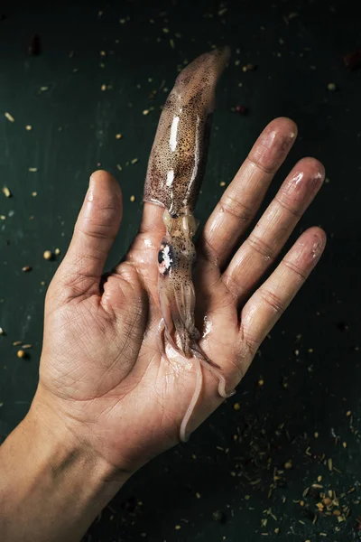 Man met een rauwe inktvis in zijn vinger — Stockfoto