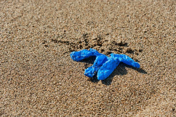 Крупный План Голубой Использованной Латексной Перчатки Брошенной Мокрый Песок Побережья — стоковое фото