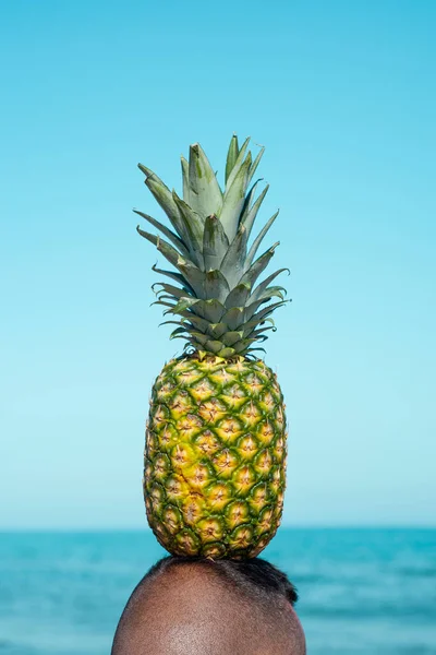一个男人的特写镜头 从后面的海滩上看到 在大海前 头上顶着一个菠萝 — 图库照片