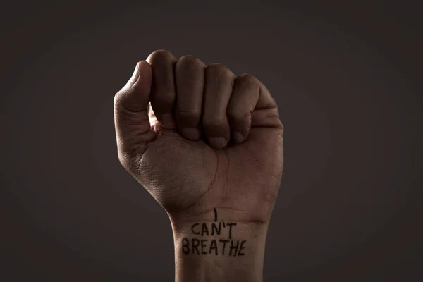 closeup of the raised fist of a man with the text I cant breathe in his wrist, as it is used as slogan in the George Floyd protests in response to police brutality and racism in the United States