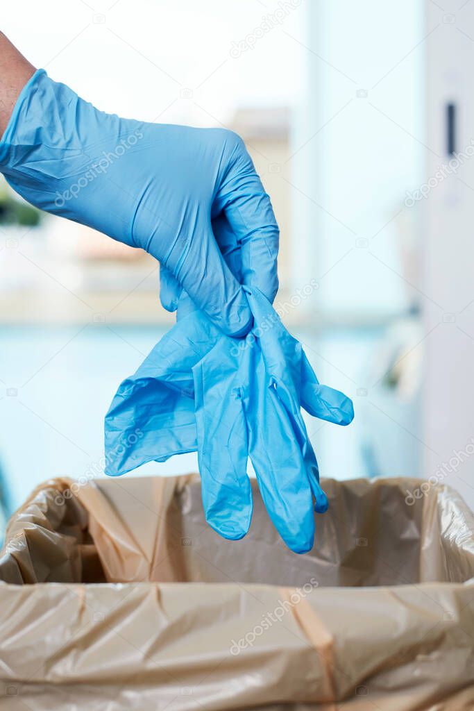 closeup of a man throwing a used latex glove to the trash can