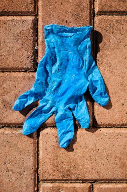 Şehrin kaldırımına atılmış mavi lateks eldivenin yüksek açılı görüntüsü.