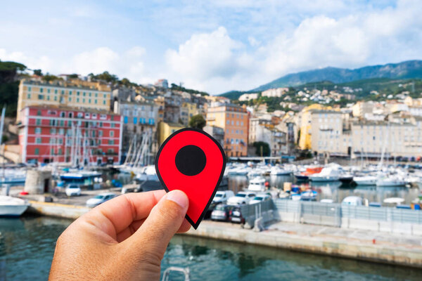 closeup of the hand of a young caucasian man with a red marker pointing the Vieux Port, the Old Port of Bastia, in Corsica, France