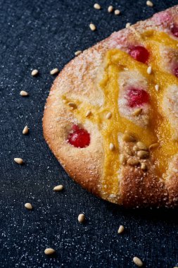 Katalonya, İspanya 'dan gelen tipik bir tatlı olan Coca de Sant Joan' a yakın plan. Aziz Johns arifesinde, çam fıstığı serpiştirilmiş siyah kumaştan bir yüzey üzerinde yenir.