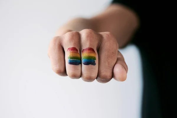 在一个年轻的高加索人的拳头上的彩虹旗的特写 在一个非白色的背景下 — 图库照片
