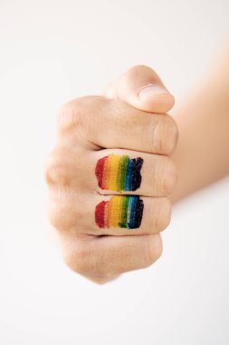 closeup of a rainbow flag in the fist of a young caucasian person, against an off-white background clipart