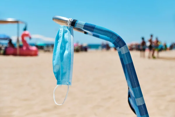 Close Uma Máscara Cirúrgica Pendurada Uma Cadeira Praia Azul Com — Fotografia de Stock