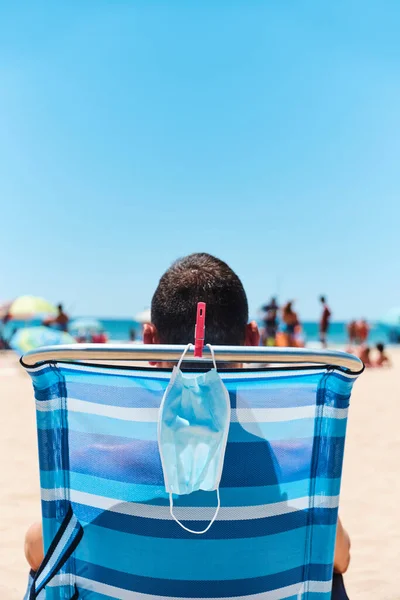 Zbliżenie Białego Mężczyzny Siedzącego Leżaku Plaży Widzianego Tyłu Jego Maska — Zdjęcie stockowe