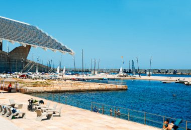 BARCELONA, SPAIN - 24 Haziran 2020: İnsanlar Barselona, İspanya 'daki Parc del Forum halk parkında okyanusta yüzerek soldaki dev heykeltraş panelini vurguluyor