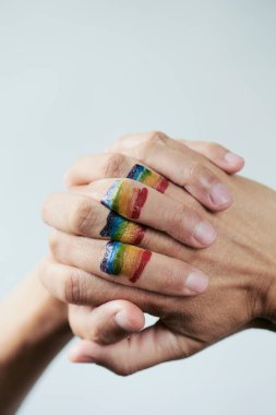 Gökkuşağı bayrağının, beyaz bir arka plana karşı genç bir Kafkasyalı 'nın sıkıca bağlı ellerinde, üzerinde boş bir boşluk olan yakın plan görüntüsü.