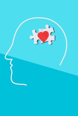 Bir adamın kafasının siluetinde bir kalp oluşturan bir yapbozun iki parçası, mavi arka planda.