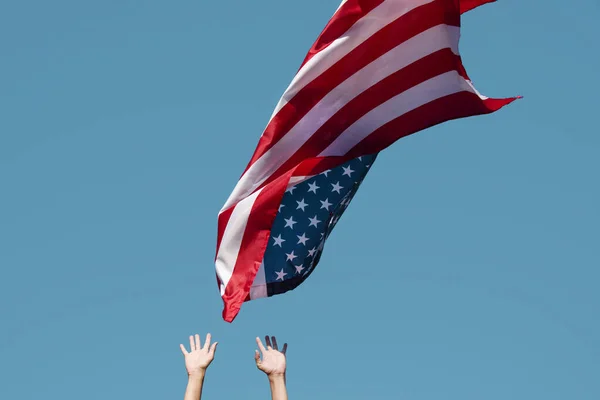 青い空に米国の旗を掲揚する若い白人男性の閉鎖 またはそれが空中を飛行する際にそれをキャッチしようとしている — ストック写真