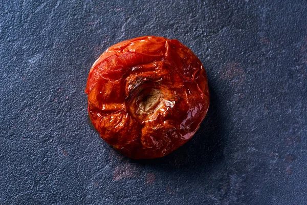 Wysoki Kąt Widzenia Nieobranego Palonego Pomidora Czarnej Kamiennej Powierzchni — Zdjęcie stockowe