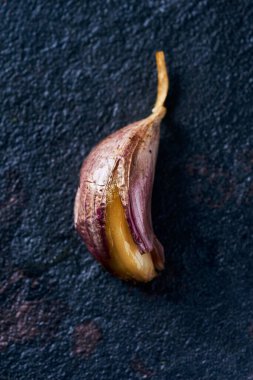 Siyah bir taş yüzeyde soyulmamış kavrulmuş sarımsağın yüksek açılı görüntüsü