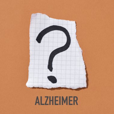 Bir parça kağıttaki soru işareti ve turuncu arkaplandaki Alzheimer.