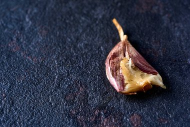 Siyah bir taş yüzeyde soyulmamış kavrulmuş sarımsağın yüksek açılı görüntüsü