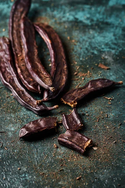 Algarrobas Maduras Sobre Una Superficie Rústica Verde Oscuro —  Fotos de Stock