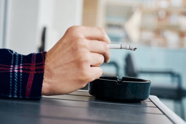 Genç, beyaz bir adamın, pijamalı, sigara içen, balkonda, evinde ya da bir otelde sigara içen bir fotoğrafı.