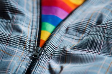 Fermuarı açık gri bir ceketin yakın çekimi içinde gay gurur bayrağı görmesine olanak sağlıyor.