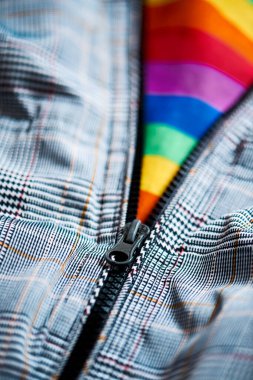 Fermuarı açık gri bir ceketin yakın çekimi içinde gay gurur bayrağı görmesine olanak sağlıyor.
