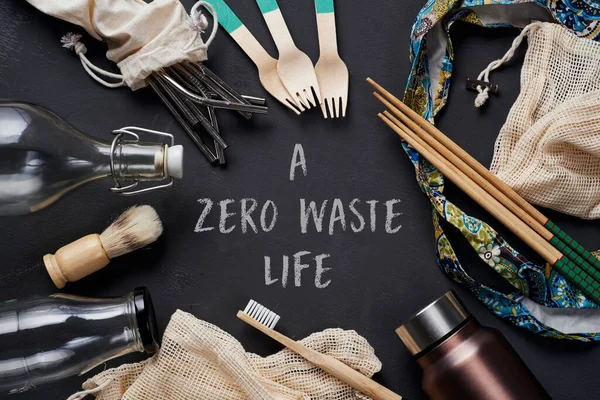一堆可持续的非塑料家用物品 如可再充填的金属和玻璃瓶 购物网袋或可重复使用的木制卫生用品 餐具和筷子 文本为零浪费生命 — 图库照片