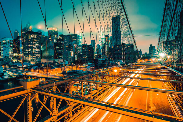 On Brooklyn Bridge at night with car traffic, NY.