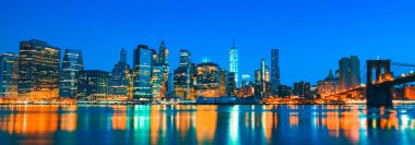 New York Şehri Manhattan şehir merkezi, alacakaranlıkta, doğu nehri üzerinde aydınlanan gökdelenlerle.