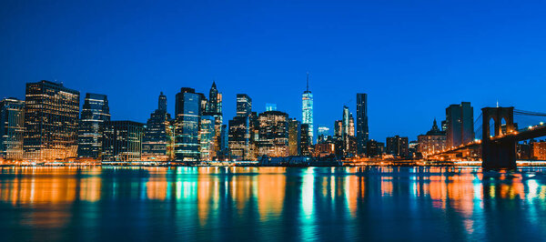 New York City Manhattan midtown at dusk with skyscrapers illuminated over east river