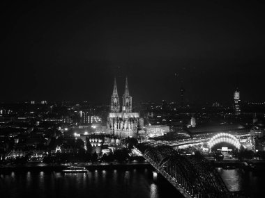 Gece görüşü Koelner Dom Sankt Petrus (anlamı St Peter Katedrali) gotik kilise ve Hohenzollern Köprüsü (anlamı Hohenzollern Köprüsü) Almanya 'nın Koeln kentindeki Rhein Nehri' ni siyah beyaz geçmektedir.
