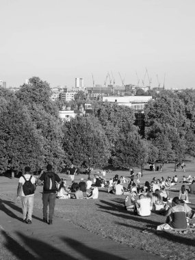 LONDON, UK - CIRCA SEPTEMBER 2019: Regent 's Park' ın kuzeyindeki Primrose Hill 'de insanlar gün batımında siyah beyaz gökyüzüne bakıyor