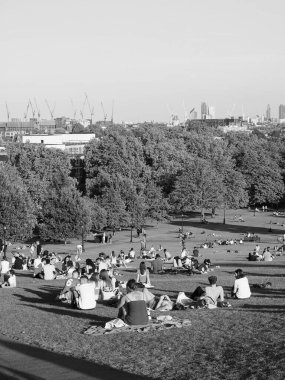 LONDON, UK - CIRCA SEPTEMBER 2019: Regent 's Park' ın kuzeyindeki Primrose Hill 'de insanlar gün batımında siyah beyaz gökyüzüne bakıyor