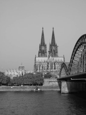 KOELN, GERMANY - CIRCA AUGust 2019: Koelner Dom Sankt Petrus (anlamı St Peter Katedrali) gotik kilise ve Hohenzollernbruecke (anlamı Hohenzollern Köprüsü) Rhein Nehri 'ni siyah beyaz geçerek