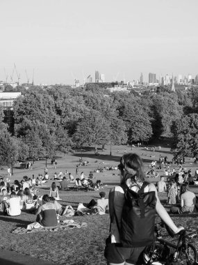 LONDON, UK - CIRCA SEPTEMBER 2019: Regent 's Park' ın kuzeyindeki Primrose Hill 'de insanlar gün batımında siyah beyaz gökyüzüne bakıyor