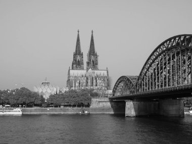 KOELN, GERMANY - CIRCA AUGust 2019: Koelner Dom Sankt Petrus (anlamı St Peter Katedrali) gotik kilise ve Hohenzollernbruecke (anlamı Hohenzollern Köprüsü) Rhein Nehri 'ni siyah beyaz geçerek