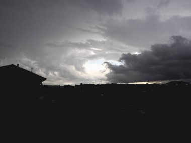 Bulutlu gri fırtınalı gökyüzü ve karanlık şehir silueti arka plan olarak kullanışlı