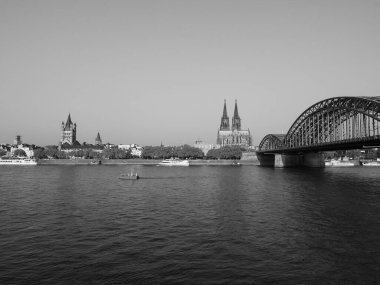 KOELN, GERMANY - CIRCA AUGust 2019: Koelner Dom Sankt Petrus (anlamı St Peter Katedrali) gotik kilise ve Hohenzollernbruecke (anlamı Hohenzollern Köprüsü) Rhein Nehri 'ni siyah beyaz geçerek