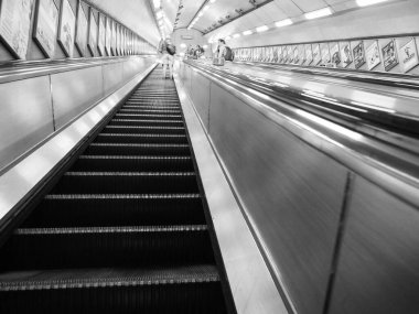LONDON, İngiltere - CIRCA SEPTEMBER 2019: Siyah beyaz Londra metro istasyonunda yürüyen merdivenler