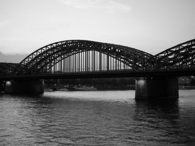 KOELN, GERMANY - CIRCA AUGust 2019: Hohenzollernbruecke (Hohenzollern Köprüsü) siyah beyaz Rhein Nehri 'ni geçer