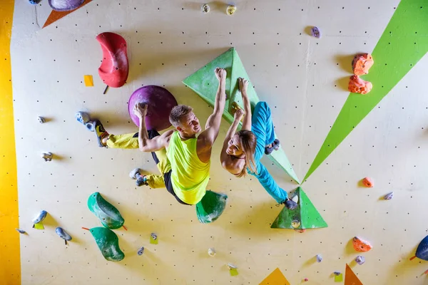 攀岩者在抱石赛体育馆爬上悬垂墙 看着相机和微笑 — 图库照片