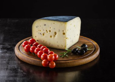 Peynir, domates ve zeytin siyah arka plan üzerinde ahşap tahta üzerinde parça